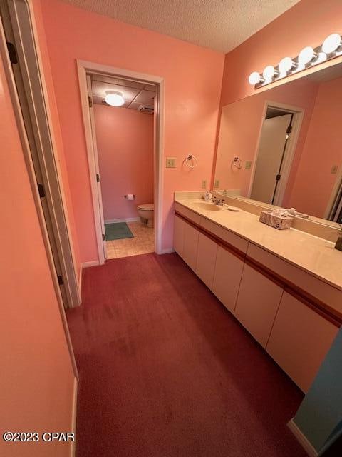 bathroom with a textured ceiling, vanity, and toilet