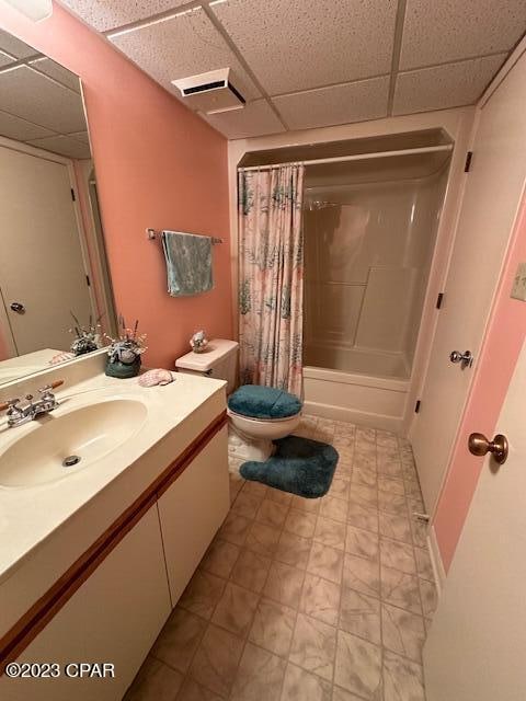 full bathroom with shower / tub combo, a paneled ceiling, vanity, and toilet