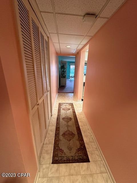 corridor featuring a paneled ceiling and light tile patterned flooring