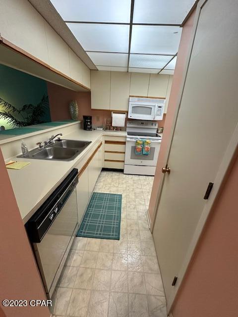 kitchen with cream cabinetry, sink, and white appliances