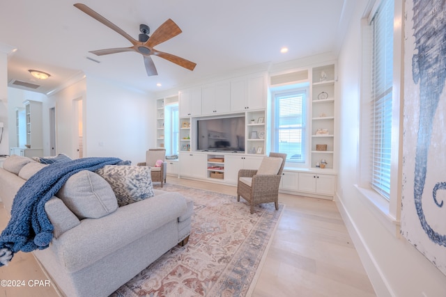 living room with ornamental molding, light wood-type flooring, ceiling fan, and built in features