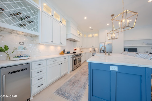 kitchen with custom exhaust hood, tasteful backsplash, decorative light fixtures, a kitchen island with sink, and stainless steel appliances