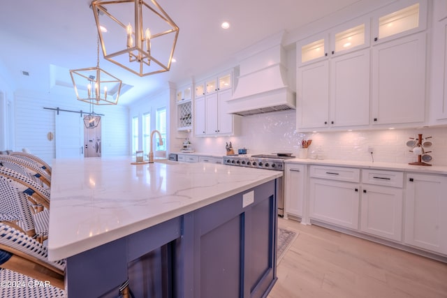 kitchen featuring sink, decorative light fixtures, stainless steel stove, an inviting chandelier, and a barn door