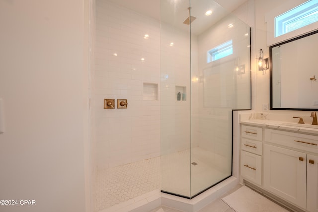 bathroom with tiled shower, vanity, and tile patterned flooring