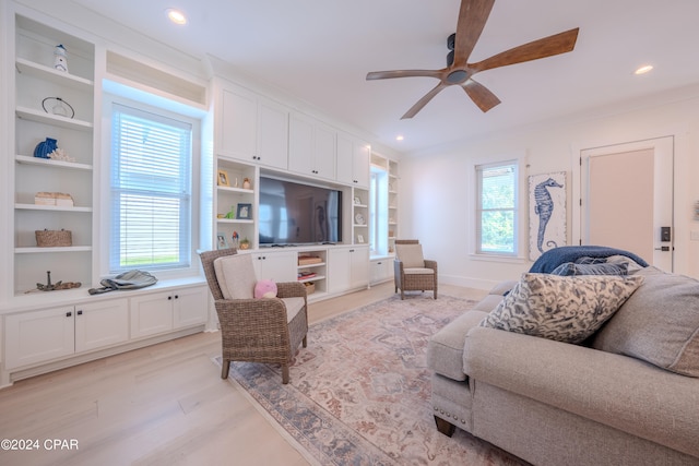 living room featuring light hardwood / wood-style flooring, a wealth of natural light, ceiling fan, and built in features