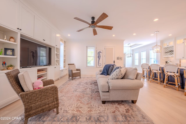 living room featuring ceiling fan with notable chandelier and light wood-type flooring