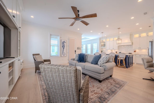 living room with ceiling fan, light hardwood / wood-style flooring, and ornamental molding