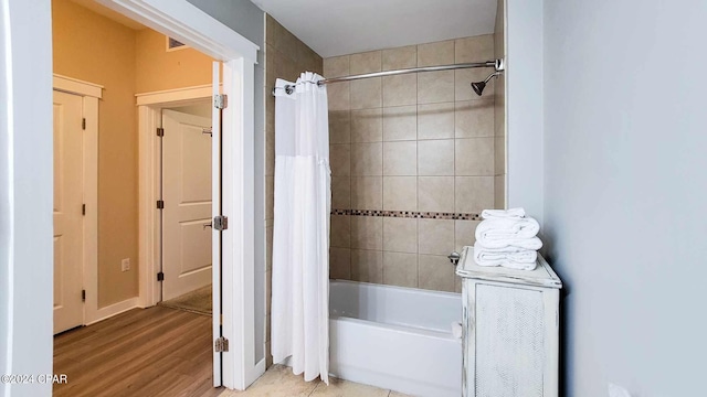 bathroom featuring hardwood / wood-style flooring and shower / bathtub combination with curtain