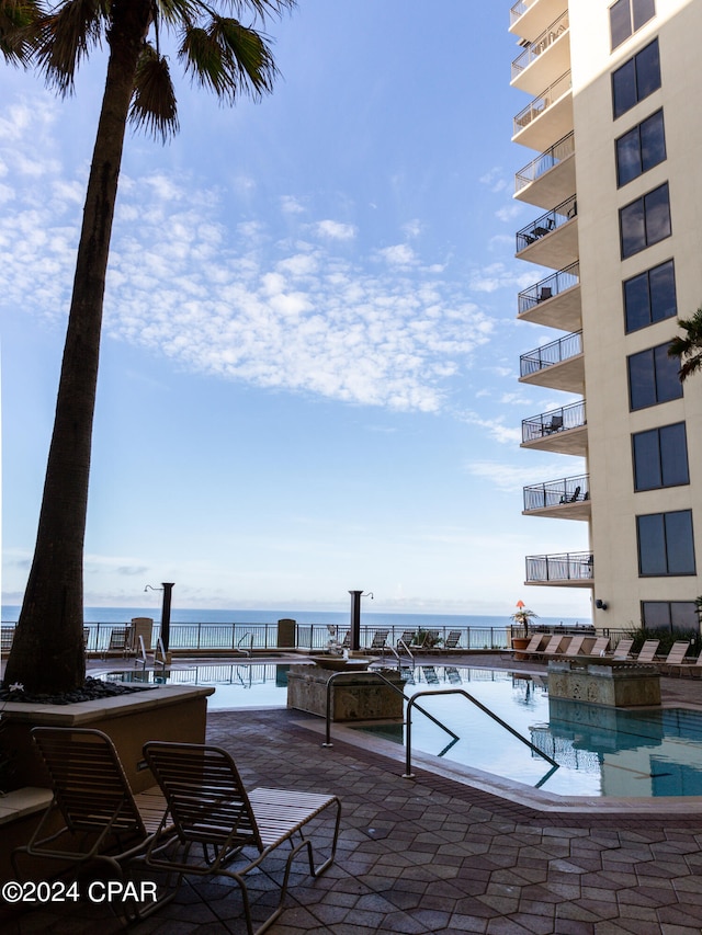 view of swimming pool featuring a patio area and a water view