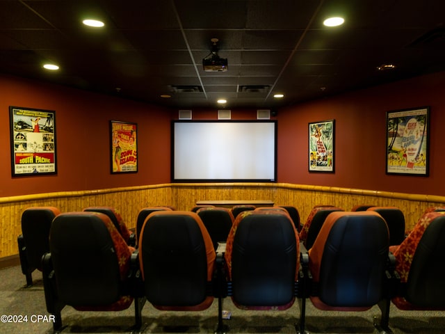 home theater room with carpet, a drop ceiling, and wooden walls