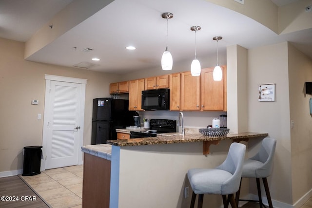 kitchen featuring kitchen peninsula, light wood-type flooring, hanging light fixtures, and black appliances