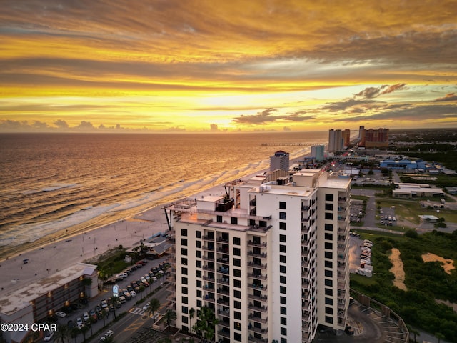 aerial view at dusk with a water view and a beach view