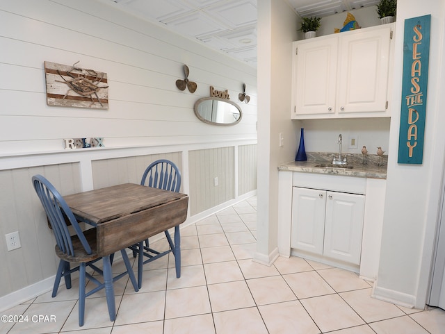 dining room with indoor wet bar, wood walls, and light tile patterned floors