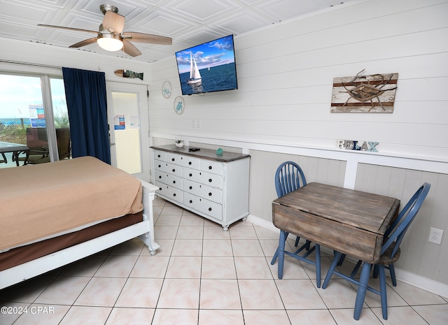 tiled bedroom featuring ceiling fan and wood walls