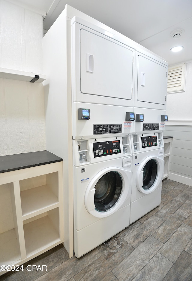 clothes washing area featuring stacked washer and clothes dryer, dark hardwood / wood-style flooring, and washer and dryer