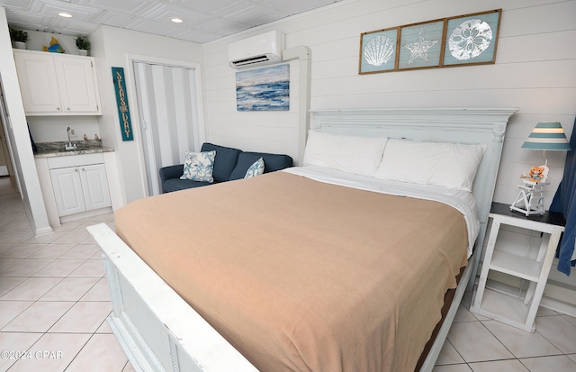 tiled bedroom featuring ensuite bath, a wall unit AC, and sink