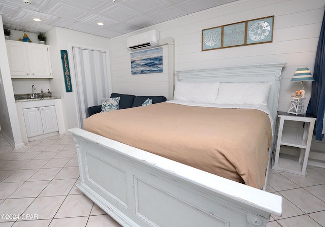 bedroom featuring an AC wall unit, light tile patterned floors, and sink