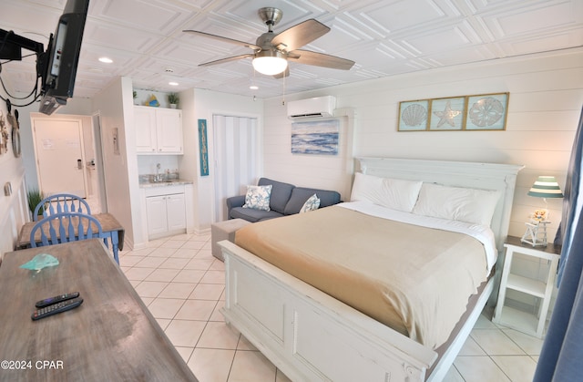 bedroom featuring light tile patterned flooring, an AC wall unit, ceiling fan, and sink