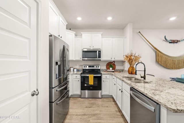 kitchen featuring light stone counters, light hardwood / wood-style floors, sink, white cabinetry, and stainless steel appliances