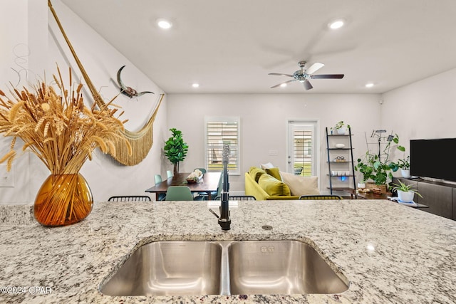 kitchen featuring light stone countertops, ceiling fan, and sink