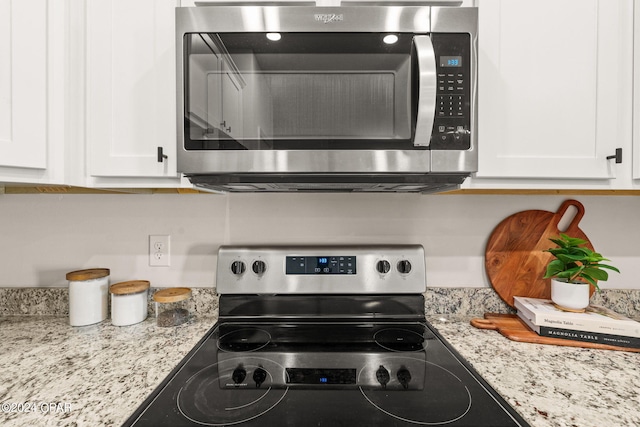 kitchen with light stone countertops, stainless steel appliances, and white cabinetry