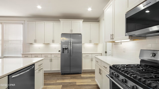 kitchen with appliances with stainless steel finishes, dark wood-type flooring, decorative backsplash, and white cabinetry