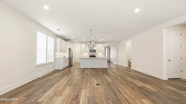 unfurnished living room with hardwood / wood-style flooring and crown molding