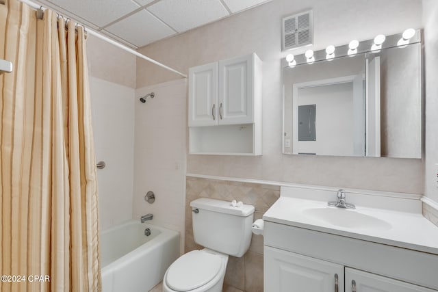 full bathroom featuring vanity, a drop ceiling, tile walls, toilet, and shower / tub combo with curtain