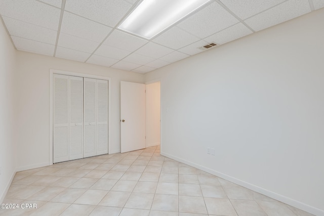 unfurnished bedroom with a drop ceiling and a closet