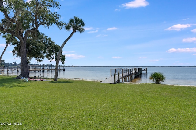 view of dock with a yard and a water view