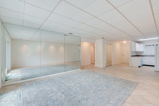 unfurnished living room featuring a paneled ceiling and sink