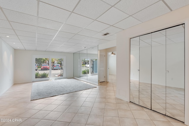 unfurnished bedroom with a closet, light tile patterned flooring, and a paneled ceiling