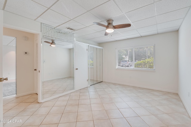 unfurnished bedroom featuring ceiling fan, light tile patterned flooring, and a paneled ceiling