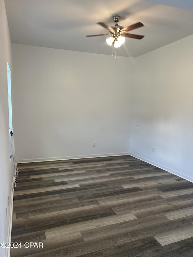 spare room with baseboards, ceiling fan, and dark wood-type flooring