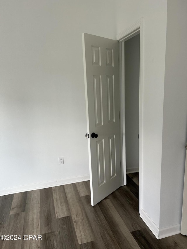 spare room featuring baseboards and dark wood finished floors