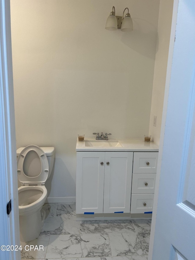 bathroom featuring marble finish floor, vanity, toilet, and baseboards