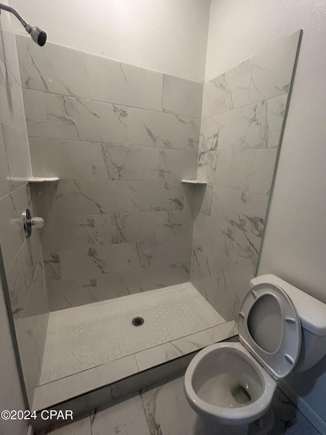 full bathroom with marble finish floor, toilet, and a stall shower