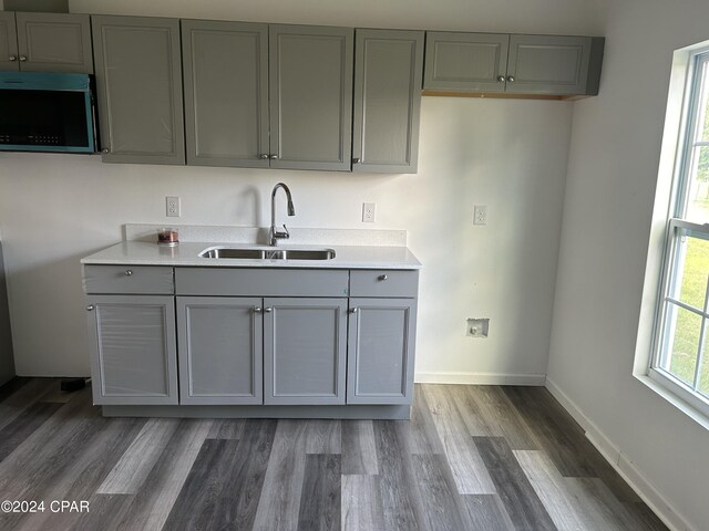 kitchen with a sink, gray cabinets, and wood finished floors
