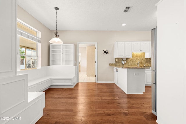 kitchen featuring pendant lighting, dark stone countertops, white cabinetry, and dark hardwood / wood-style flooring