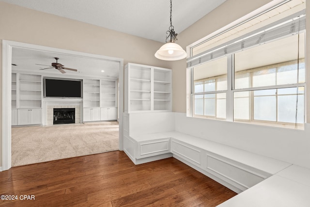 interior space with ceiling fan, dark hardwood / wood-style floors, and a tile fireplace