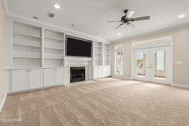 unfurnished living room featuring a textured ceiling, ornamental molding, a tiled fireplace, and ceiling fan