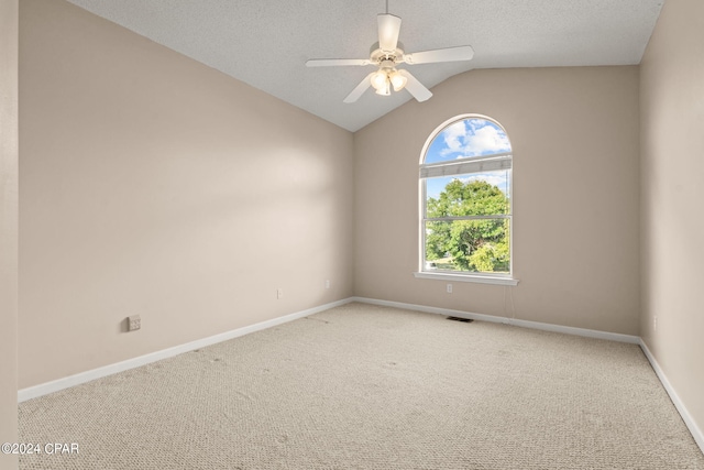 carpeted empty room with a textured ceiling, vaulted ceiling, and ceiling fan