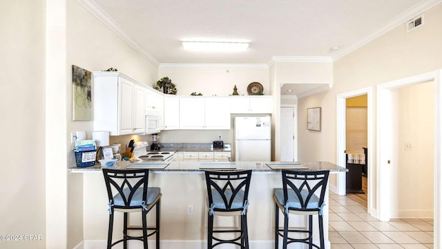 kitchen with kitchen peninsula, ornamental molding, white appliances, white cabinetry, and a breakfast bar area