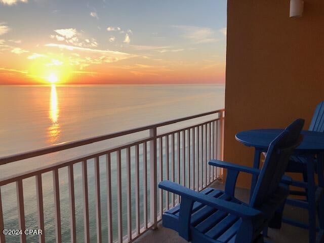 balcony at dusk featuring a water view