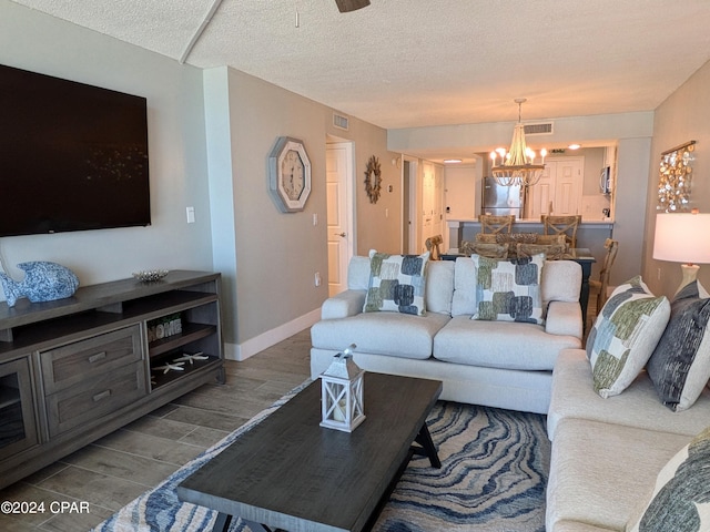 living room with ceiling fan with notable chandelier and a textured ceiling