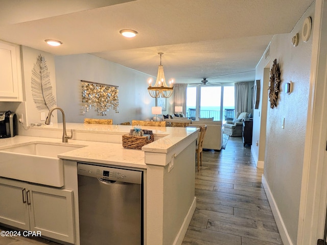 kitchen with pendant lighting, sink, white cabinets, stainless steel dishwasher, and light stone counters