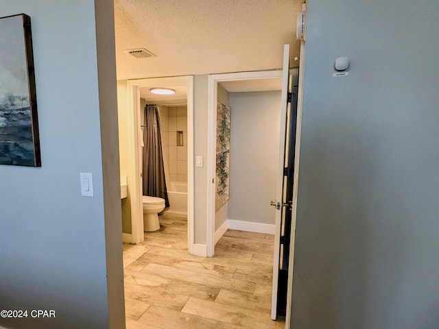 hallway featuring a textured ceiling and light wood-type flooring