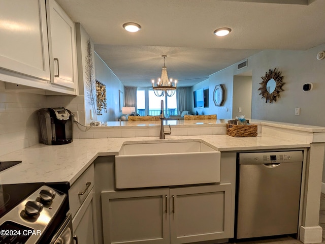 kitchen with stainless steel appliances, light stone countertops, sink, and an inviting chandelier