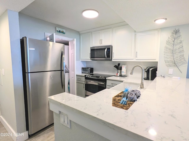 kitchen featuring white cabinetry, stainless steel appliances, light hardwood / wood-style flooring, and backsplash