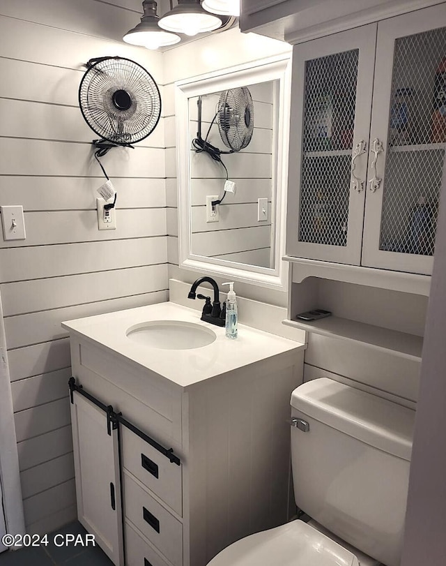 bathroom with wood walls, vanity, and toilet